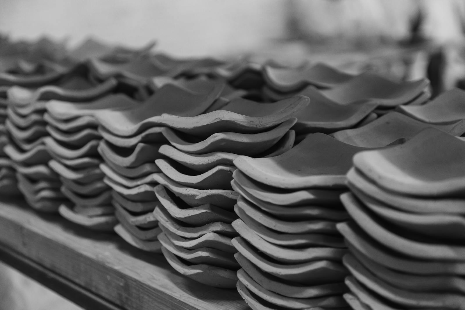 Monochrome image of neatly stacked clay roof tiles in a construction setting. {{brizy_dc_image_alt imageSrc=